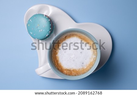 
cup of cappuccino on a saucer in the shape of a heart. Still life in blue tones.