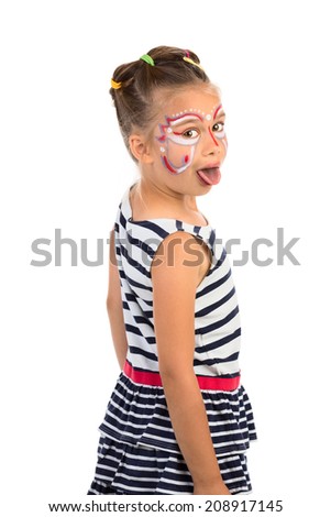 Little girl with an abstract paint on her face looking over her shoulder and showing her tongue, isolated