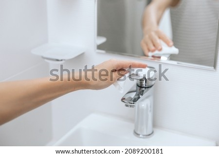 Cleaning the sink faucet with a microfiber cloth. Sanitize surfaces prevention in hospital and public spaces against corona virus. Woman hand using wet wipe. Cleaning the bathroom. Royalty-Free Stock Photo #2089200181