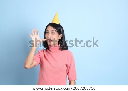 The young Asian woman wearing pink clothes standing on the blue background.