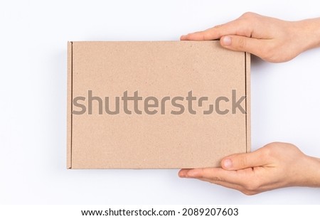 Brown cardboard box in delivery man hands, mockup, on a white background, top view  Royalty-Free Stock Photo #2089207603