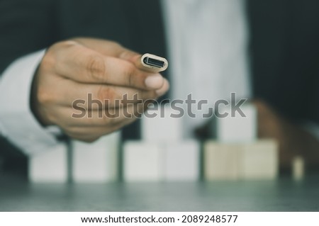 A man in suit is showing a wooden usb stick