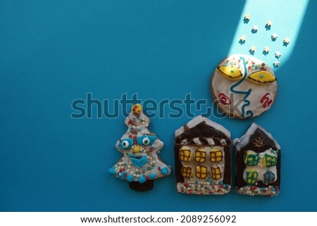 Traditional Christmas Gingerbread  Houses On The Blue Sheet Of Paper. Festive Sweet Gift Objects And Sun Light.