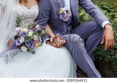 Couple hugging on their wedding. Trendy color of the year 2022 in wedding. Bride holding bouquet and embracing groom in Very Peri suit. Royalty-Free Stock Photo #2089264411
