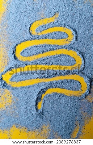 Spruce, a symbol of the New Year and Christmas, is drawn on a blue powder on a yellow background. Holiday concept. Top view. 