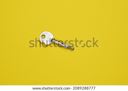 Key on a yellow background, top view. Trendy colorful photo. Trendy minimal flat lay concept.