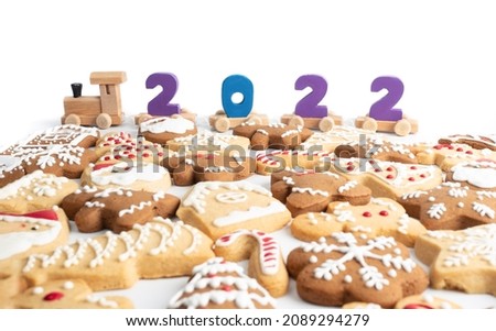 year of 2022 printed on wooden train on white background and with gingerbread cookies on foreground