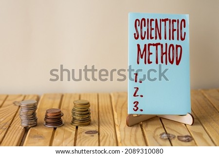Text sign showing Scientific Method. Internet Concept Principles Procedures for the logical hunt of knowledge Empty Piece Of Paper On Holder Beside Stockpile Of Coins Over Desk.
