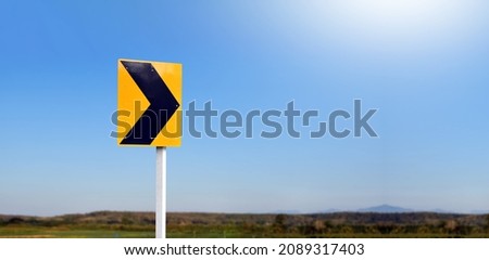 Right chevron traffic sign, this sign warns you of a change in direction or narrowing of the road. You may find these signs on the outside of a sharp curve or on approaches to a narrow bridge.