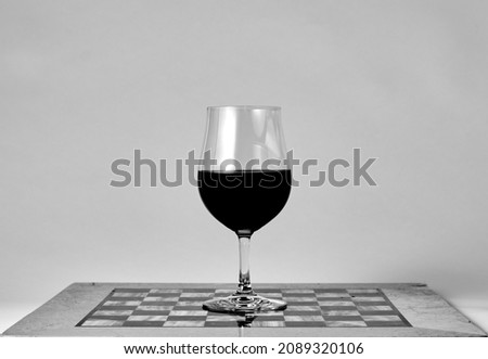 Red wine glass standing on the chessboard. Close-up macro shot on a white background. Black and white photo. Wine glasses. Chess game. win the game.