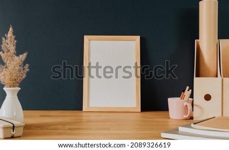 Empty wooden frame on wooden desk with stationery 