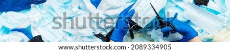 Scissors and a cut medical face mask that was used before the garbage was collected to prevent the mask from being resold during the coronavirus outbreak on a blue background