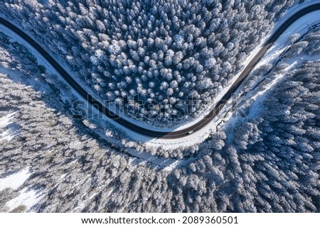 Natural winter landscape from air. Aerial view on the road and forest at the winter time. Winter chill. Forest and snow. The photo is in high resolution.