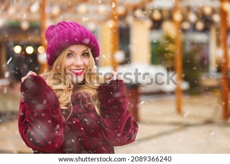Lifestyle shot of a lovely woman walking at the street market during snowfall. Empty space