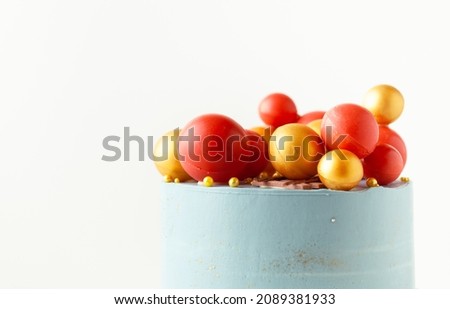 Christmas cake with blue cream cheese frosting decorated with red and gold chocolate spheres on the white background. Happy New Year