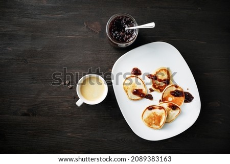 Pancakes with jam and coffee cup on wooden table background. Flat lay.