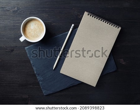 Photo of blank kraft notepad, pencil and coffee cup. Branding mock up. Top view. Flat lay.