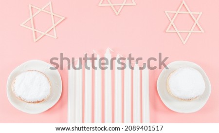 Nine white, two donuts with powder and three wooden stars of David candles lie on a pink background with copy space in the center, flat lay close-up. Hanukkah Celebration Concept.
