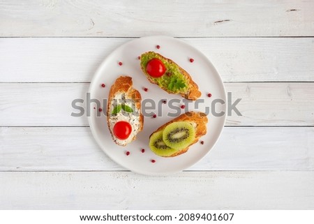 Three mini sandwiches on a plate on wooden background