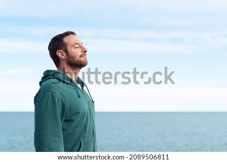 Relaxed man breathing fresh air with the sea at the background.