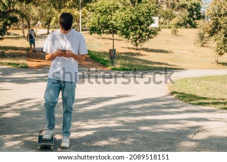 teenager on the street with mobile phone and skateboard