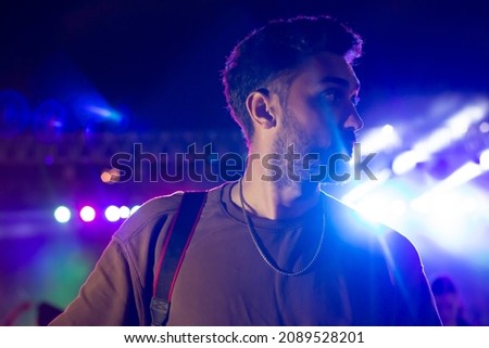 A handsome man in concert . People in the crowd at a concert make video recordings and pics on a smartphone of published in social media.