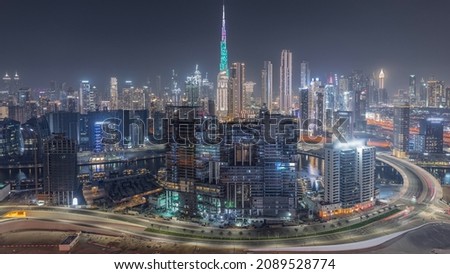 Panoramic skyline of Dubai with business bay and downtown district night timelapse. Aerial view of many modern skyscrapers and building under construction. United Arab Emirates.