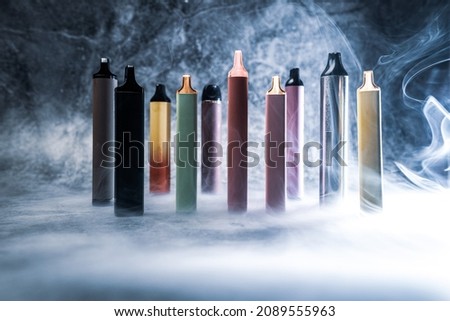 multicolored electronic cigarettes vape on dark background with smoke. High quality photo Royalty-Free Stock Photo #2089555963