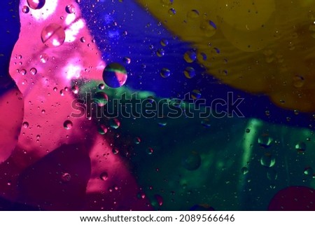 The picture shows a macro shot of water bubbles shot against a blue and pink background.