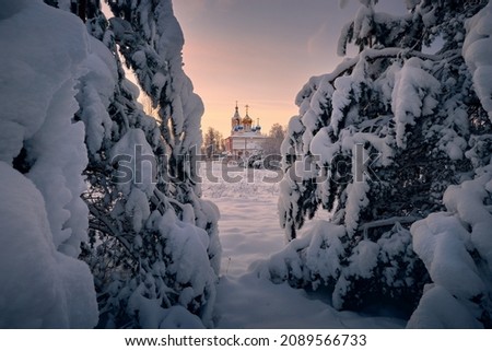 Country church on a frosty winter day with a view from the forest