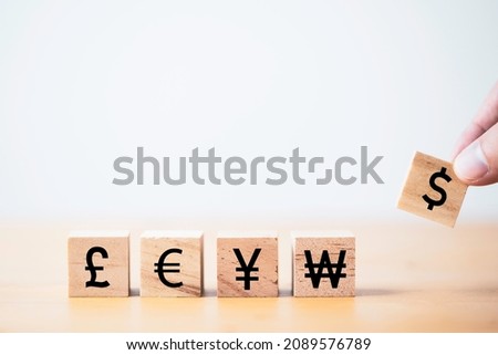 Hand putting dollar sign which print screen on wooden cube block for currency exchange and money transfer concept.