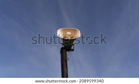 Old loudspeaker on the black pole against a blue sky background

