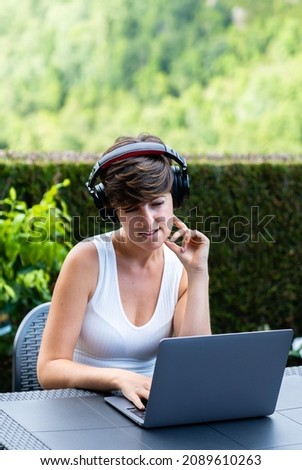 Mid woman teleworking with wireless headset and laptop in rural area.