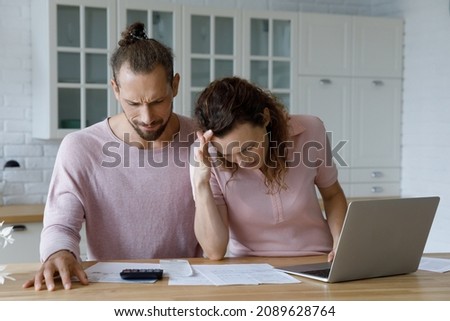 Frustrated concerned millennial married couple calculating overspend budget, doing paperwork job at laptop, talking about financial problems, insurance, mortgage, fees, loan conditions, bankruptcy Royalty-Free Stock Photo #2089628764