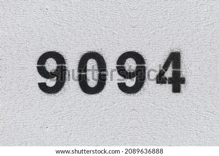 Black Number 9094 on the white wall. Spray paint. Number nine thousand ninety four.