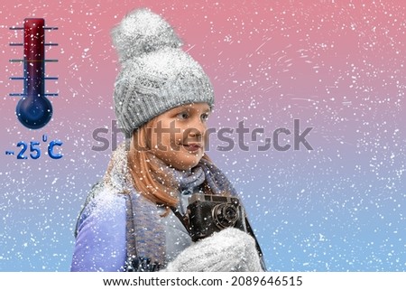 A girl in winter clothes smiles and holds a camera in her hands. Fashionable child takes pictures in winter. Young woman in outerwear is engaged in photography. Snowing . Frost on the eyelashes.
