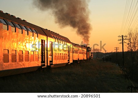 Steam train starting from the station during sunset
