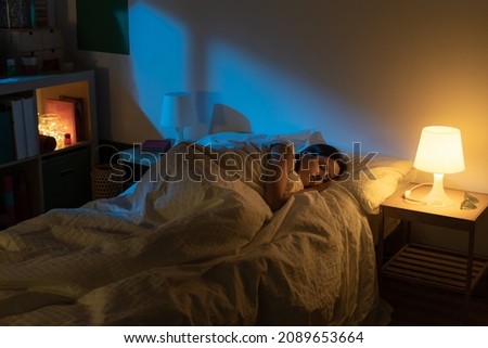 Beautiful girl suffering from insomnia lying in her bed with Blue Colors from the moon. Royalty-Free Stock Photo #2089653664