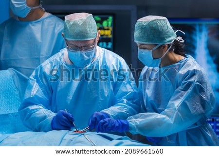 Multiracial team of professional medical surgeons performs the surgical operation in a modern hospital. Doctors are working to save the patient. Medicine, health, cardiology and transplantation. Royalty-Free Stock Photo #2089661560