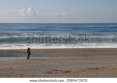 Foam waves on sandy beach and photographer silhouette, sea sand background.