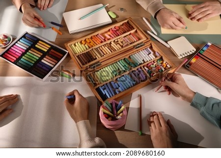 Artists drawing with soft pastels and pencils at table, above view