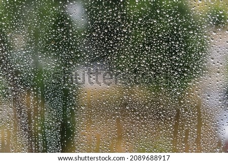 Rain drops on a window, blurry background in the back, wallpaper texture of water droplets