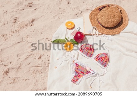 Wool bikini, hat, fruits on the beach sand through sunny day
