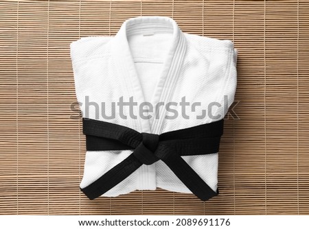 Martial arts uniform with black belt on bamboo mat, top view Royalty-Free Stock Photo #2089691176