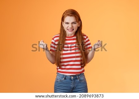 Annoyed pissed redhead female lose competition, clench fists angry grimacing evil hateful face, pressured, hate unfair results, stand orange background bothered, depressed and irritated
