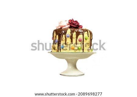 Birthday layer cake decorated with chocolate pieces and happy birthday text, hazelnuts and roses flowers isolated on white