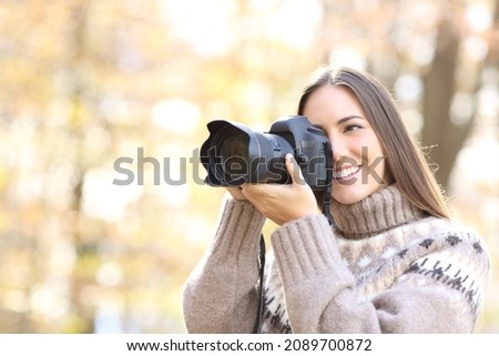 Happy woman taking photos with a professional dslr camera in nature