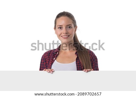 Young beautiful woman smiling showing blank white placard billboard sign. Casual caucasian female model with friendly smile. Isolated on white background