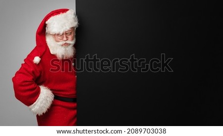 Santa Claus with black paper billboard with copy space for text , surprised facial expression