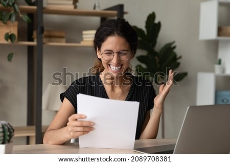 Overjoyed young Hispanic woman feel euphoric read good news in paper letter at home office. Smiling Latino female triumph get promotion offer or notice in paperwork correspondence. Success concept. Royalty-Free Stock Photo #2089708381